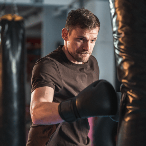 man wearing kickboxing gloves punch bag